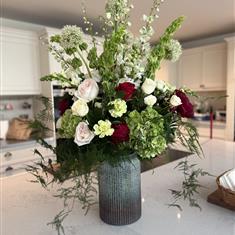 Tall vase of green, red and pink flowers
